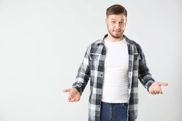 Confused young man on light background — Stock Photo, Image