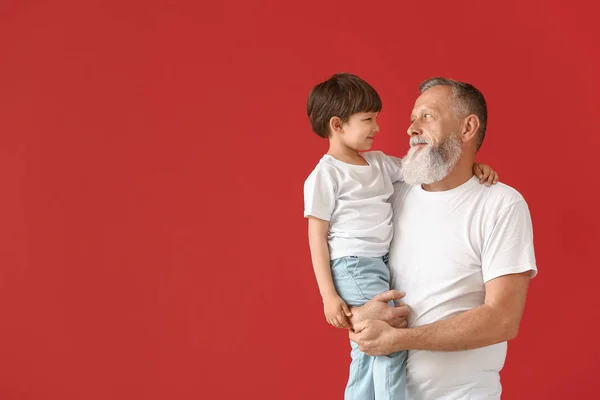 Cute little boy with grandfather on color background — Stock Photo, Image