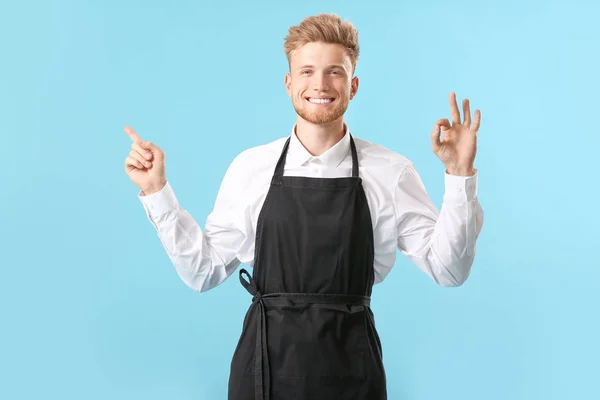 Handsome male chef pointing at something and showing OK on color background — Stock Photo, Image