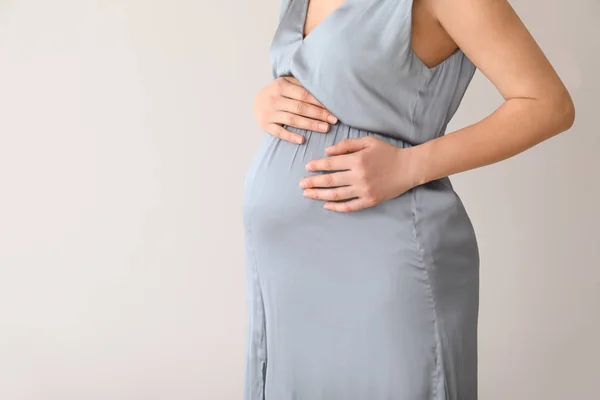 Młoda kobieta w ciąży na jasnym tle — Zdjęcie stockowe