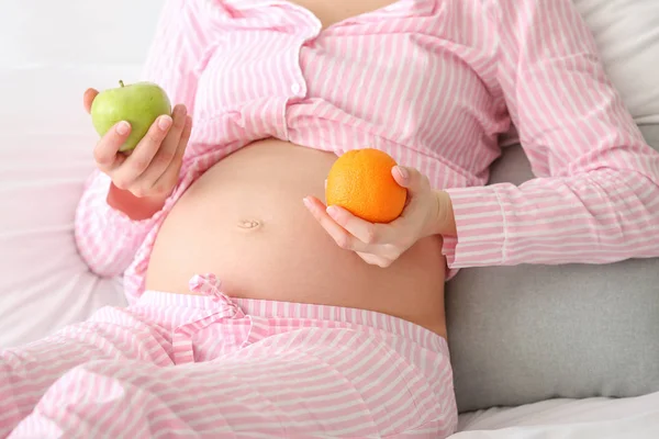 Junge schwangere Frau mit Früchten im Schlafzimmer — Stockfoto