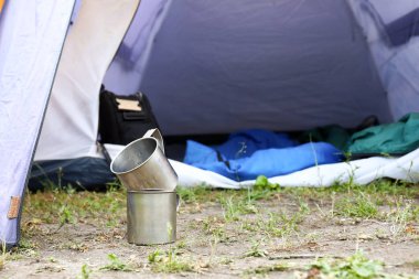Kamp çadırı yakınında yerde metal kupalar