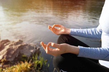 Güzel genç kadın nehir kenarında yoga yapıyor.