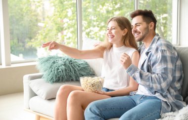 Mutlu çift evde televizyon izliyor.