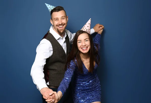 Feliz pareja joven en sombreros de fiesta en el fondo de color —  Fotos de Stock