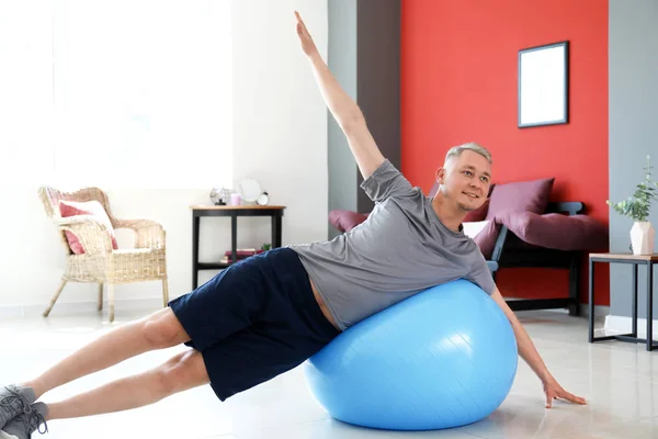 Young man doing exercise with fitball at home — Stock Photo, Image