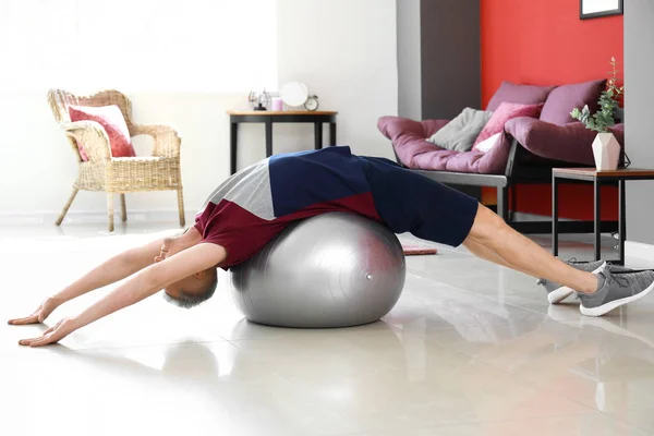 Young man doing exercise with fitball at home — Stock Photo, Image