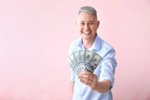 Happy young man with dollar banknotes on color background — Stock Photo, Image