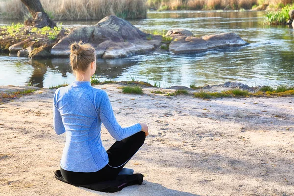 Güzel genç kadın nehir kenarında yoga yapıyor. — Stok fotoğraf