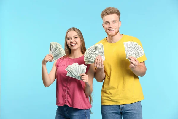 Pareja feliz con dinero en el fondo de color —  Fotos de Stock