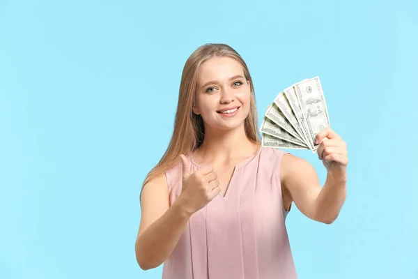 Mujer feliz con dinero mostrando gesto de pulgar hacia arriba en el fondo de color —  Fotos de Stock