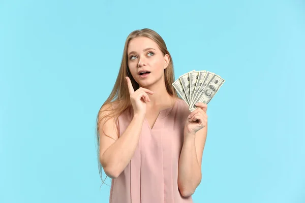 Thoughtful woman with money on color background — Stock Photo, Image