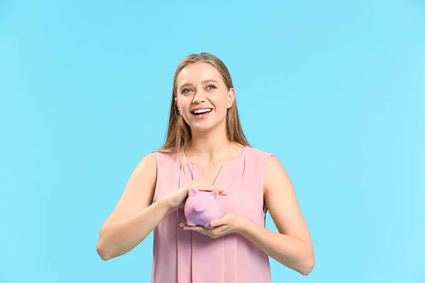 Happy woman with piggy bank on color background — Stock Photo, Image