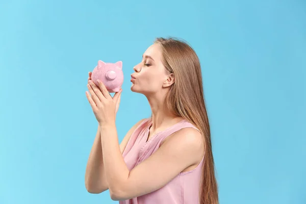 Mulher feliz com banco porquinho no fundo de cor — Fotografia de Stock