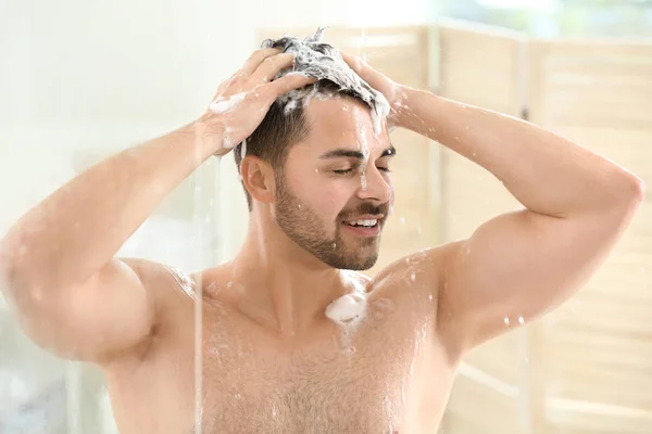 Handsome man washing hair at home