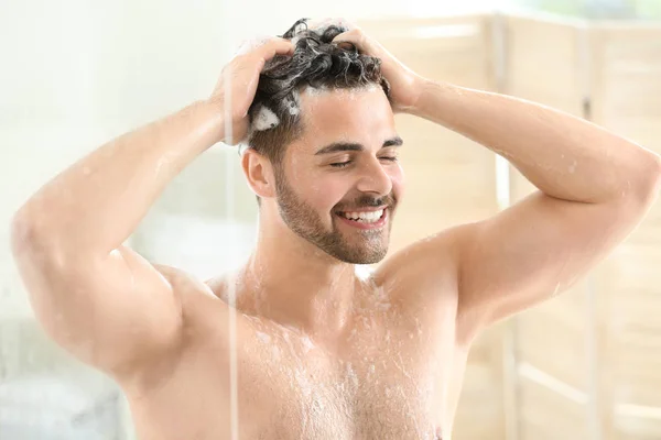 Handsome man washing hair at home