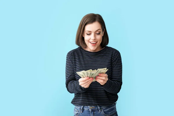 Happy young woman with money on color background — Stock Photo, Image