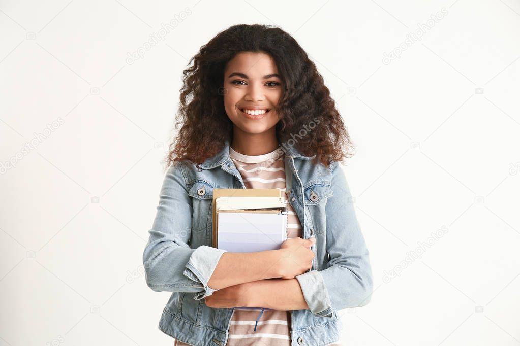 Portrait of cute African-American student on light background
