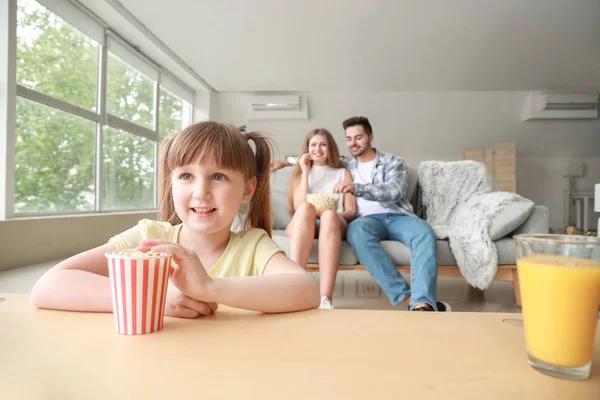 Lycklig tjej med sin familj tittar på TV hemma — Stockfoto