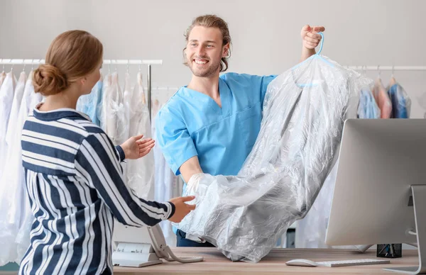 Male worker giving clothes to client in modern dry-cleaner's — Stock Photo, Image