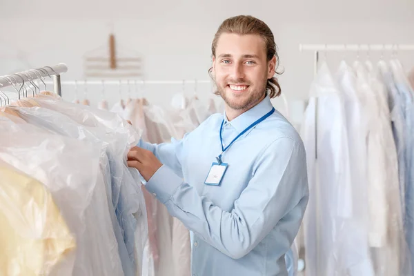 Worker of modern dry-cleaner's near rack with clothes — Stock Photo, Image