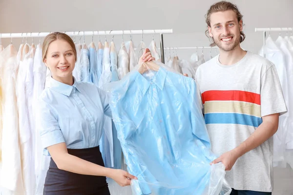 Worker giving clothes to client in modern dry-cleaner's — Stock Photo, Image