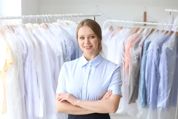 Worker of modern dry-cleaner's near rack with clothes — Stock Photo, Image