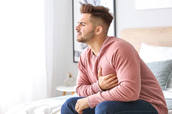 Young man suffering from heart attack at home — Stock Photo, Image