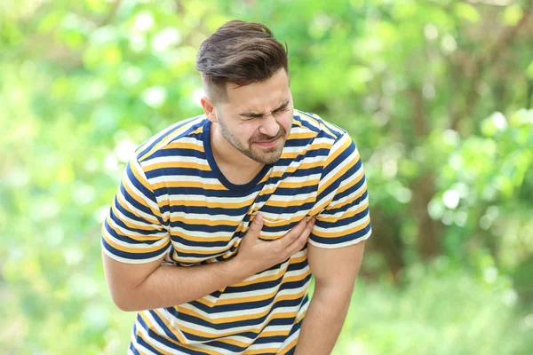 Young man suffering from heart attack outdoors — Stock Photo, Image