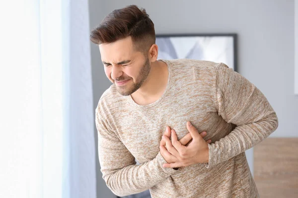 Young man suffering from heart attack at home — Stock Photo, Image