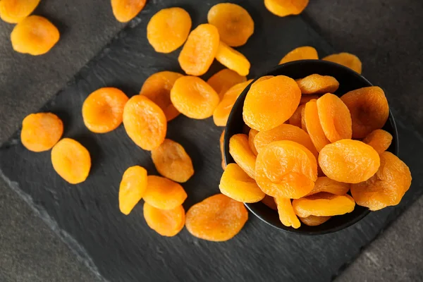 Bowl with dried apricots on slate plate — Stock Photo, Image