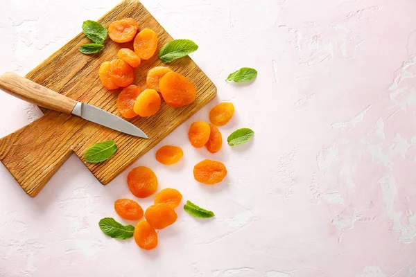 Board with dried apricots and knife on light background — Stock Photo, Image