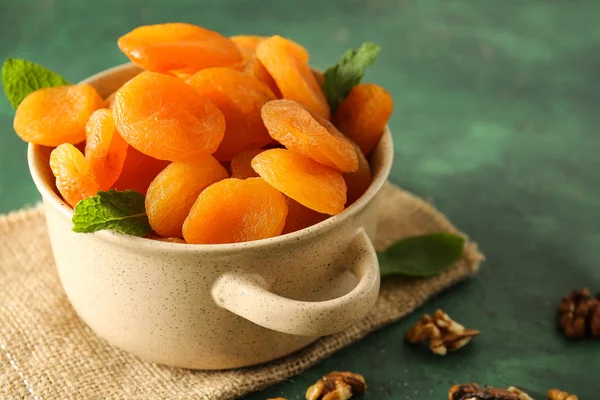 Hrnec se sušenými meruňky na barevném pozadí — Stock fotografie