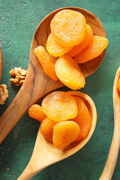 Spoons with dried apricots on color background — Stock Photo, Image