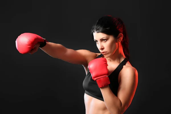 Sporty female boxer on dark background