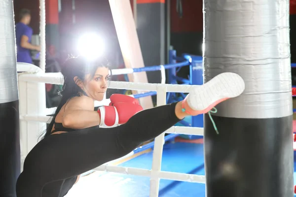 Entrenamiento de kickboxer femenino con saco de boxeo en gimnasio — Foto de Stock