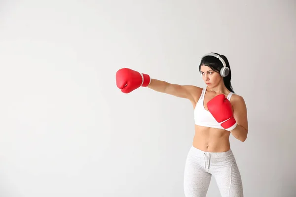 Sporty female boxer with headphones on white background — Stock Photo, Image