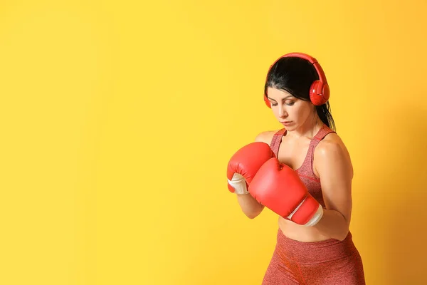 Sporty female boxer with headphones on color background — Stock Photo, Image