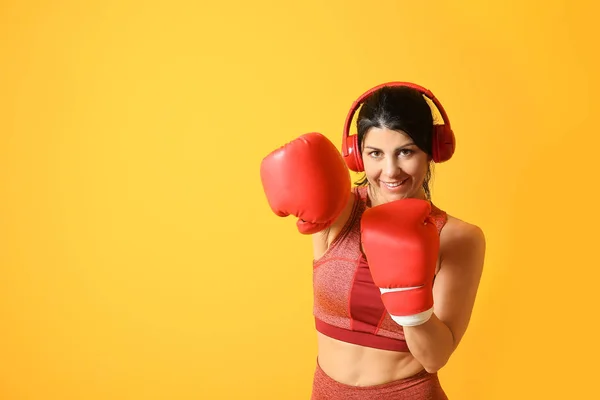 Sporty female boxer with headphones on color background — Stock Photo, Image