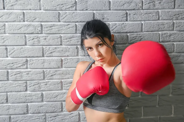 Sporty female boxer near light brick wall — Stock Photo, Image