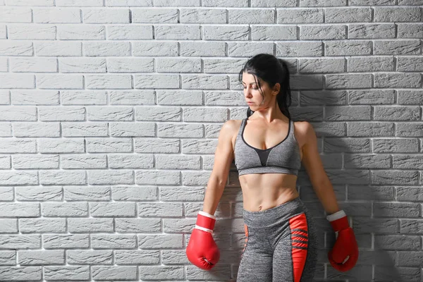 Sporty female boxer near light brick wall — Stock Photo, Image