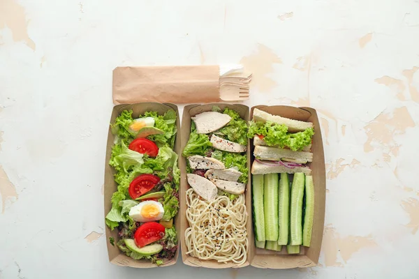Papieren dozen met heerlijk eten op lichte achtergrond — Stockfoto