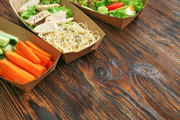 Containers met heerlijk eten op houten achtergrond — Stockfoto