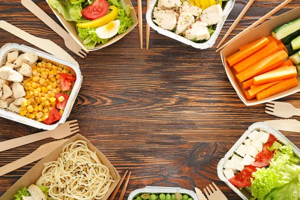 Containers met heerlijk eten op houten achtergrond — Stockfoto