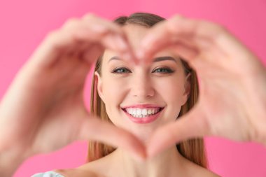 Güzel genç bir kadın, elleri renkte kalp yapıyor.