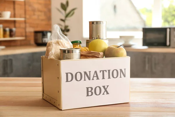 Caja con comida de donación en la mesa en la cocina — Foto de Stock