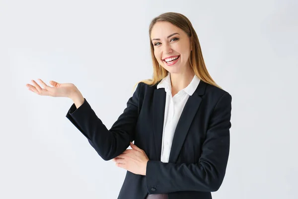 Mooie jonge zakenvrouw die iets op witte achtergrond toont — Stockfoto