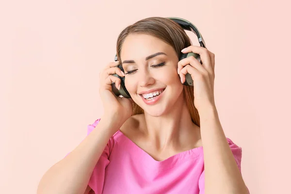Mulher bonita ouvindo música no fundo de cor — Fotografia de Stock