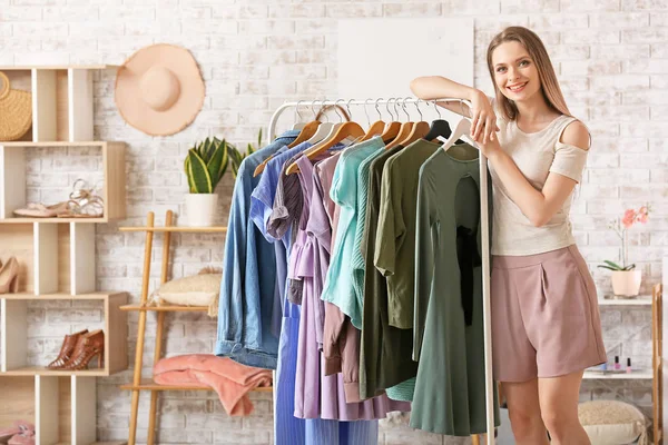 Jeune femme debout près de porte-vêtements dans le vestiaire — Photo