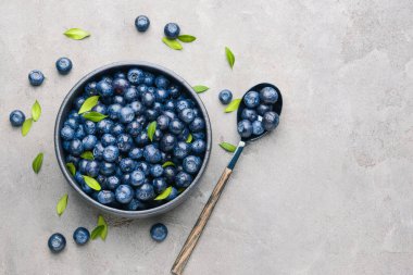 Kase ve kaşık gri arka plan üzerinde olgun yaban mersini ile